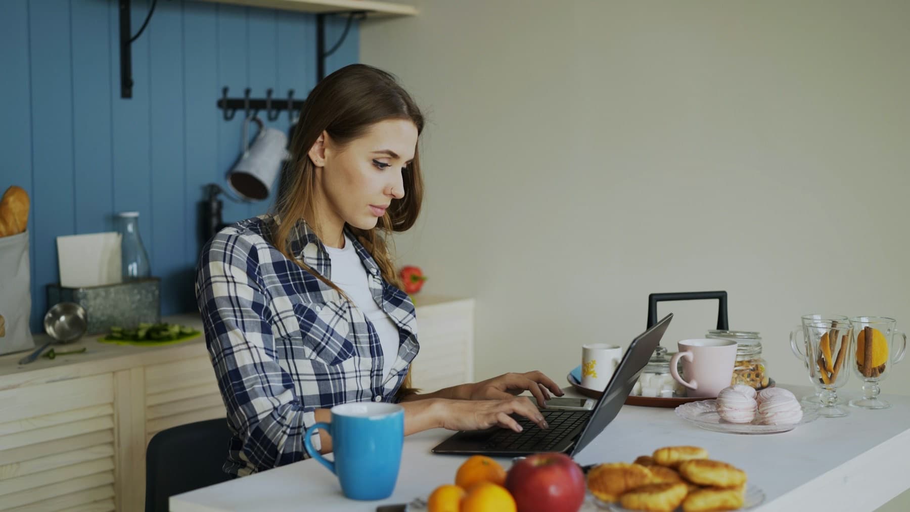 Vrouw werkt rustig op haar laptop aan de keukentafel