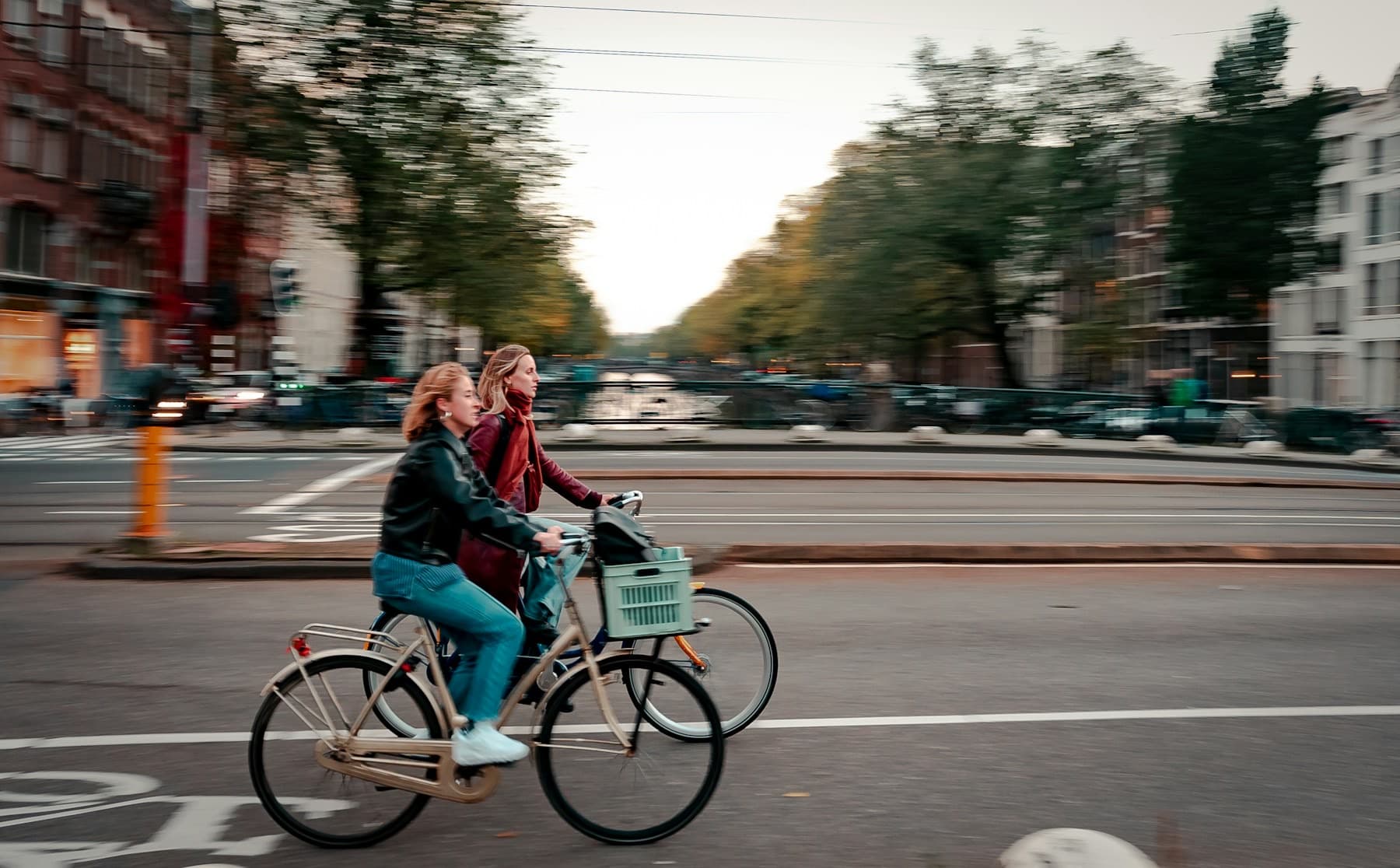 Twee vrouwen fietsen door een Amsterdamse straat